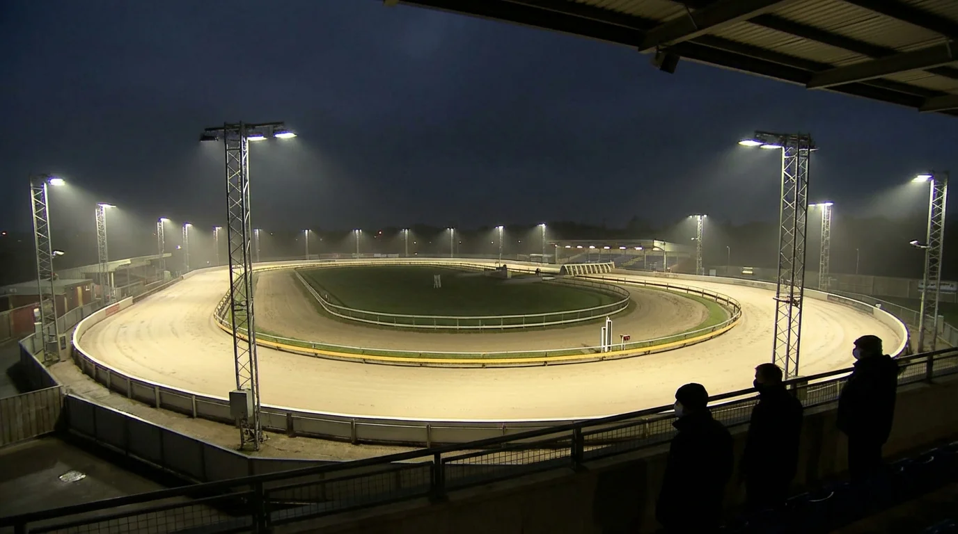 Wide view of a greyhound stadium at night with floodlights illuminating the track